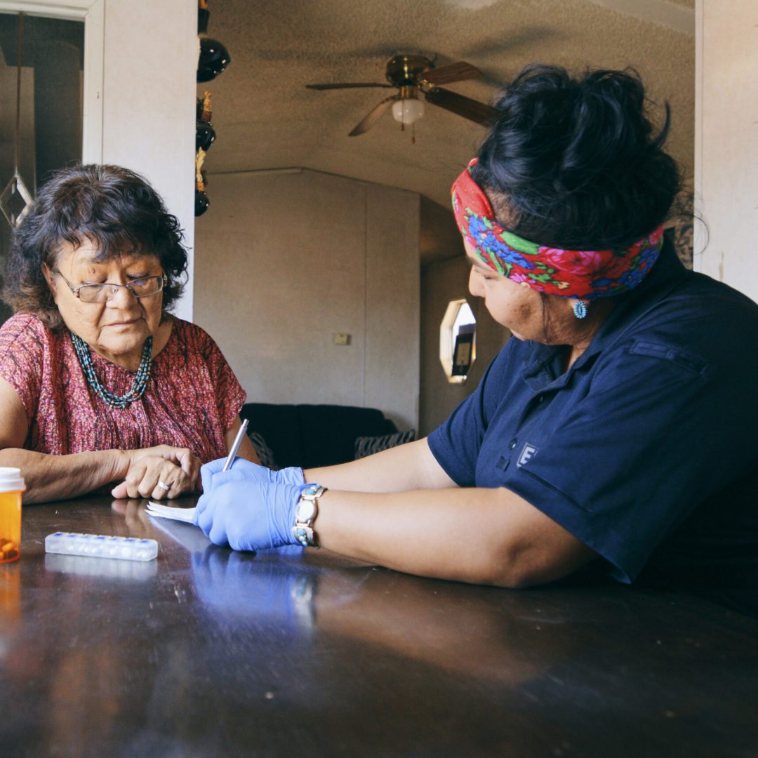 An Indigenous Navajo senior aged woman, receiving healthcare assistance in her home.
